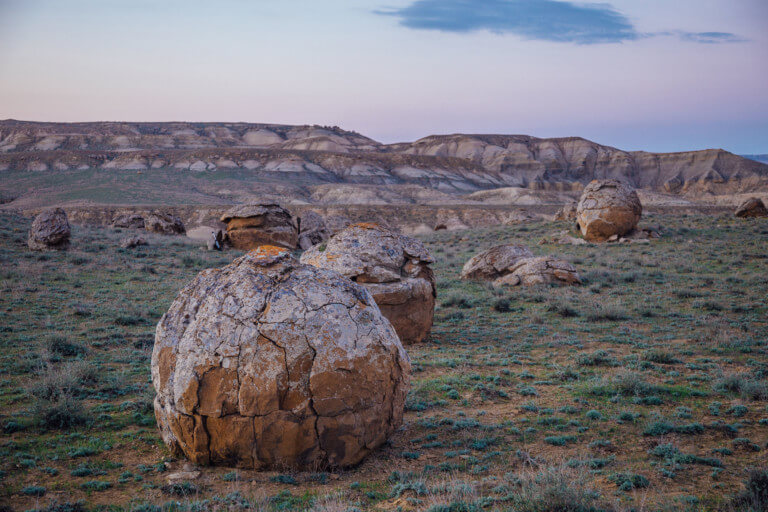 A series of spherical rocks in a grassy desert field in Torysh Valley.