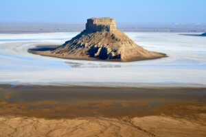 A mountain surrounded by pure white salt flats.