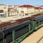 Rail carriages loaded with giant industrial pipes outside of Zhanaozen railway station.
