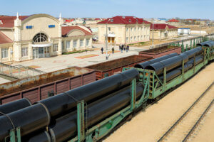 Rail carriages loaded with giant industrial pipes outside of Zhanaozen railway station.